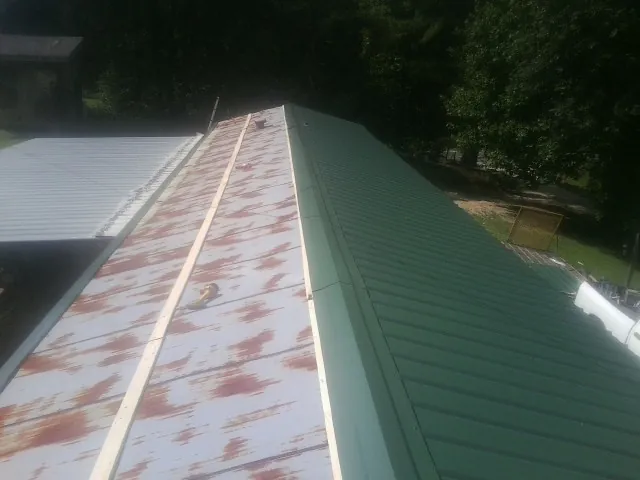 Old rusted panels beside newly installed green metal roofing — Wind Damage Roof Repair by Roofing Brothers in Moorefield