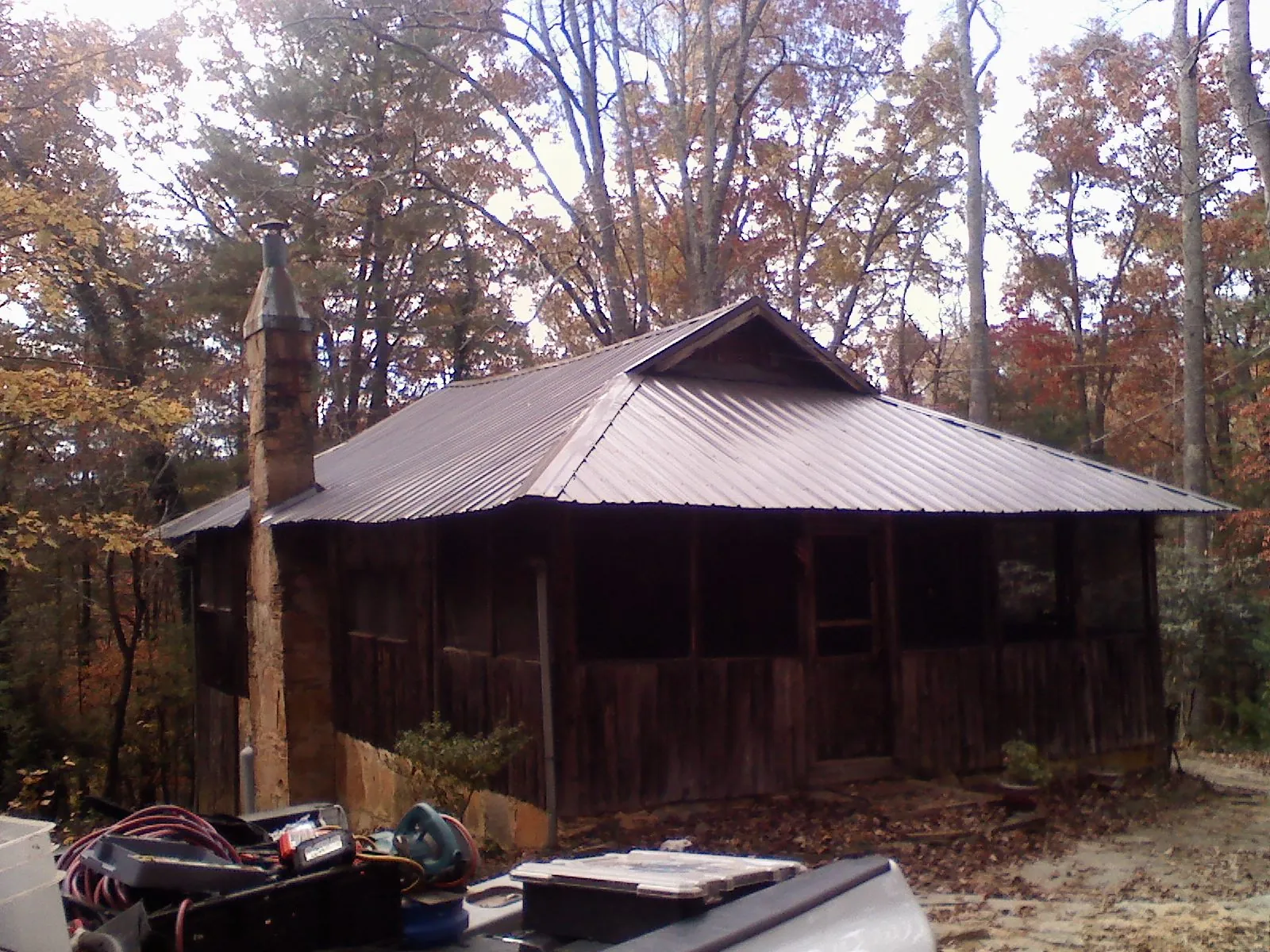 Brown metal hip roof on an old cabin with a stone chimney in Moorefield