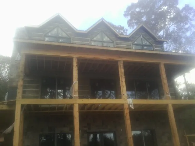 Dormers and porch framing on a large log home under construction — Roof Coating work by our crew in Moorefield